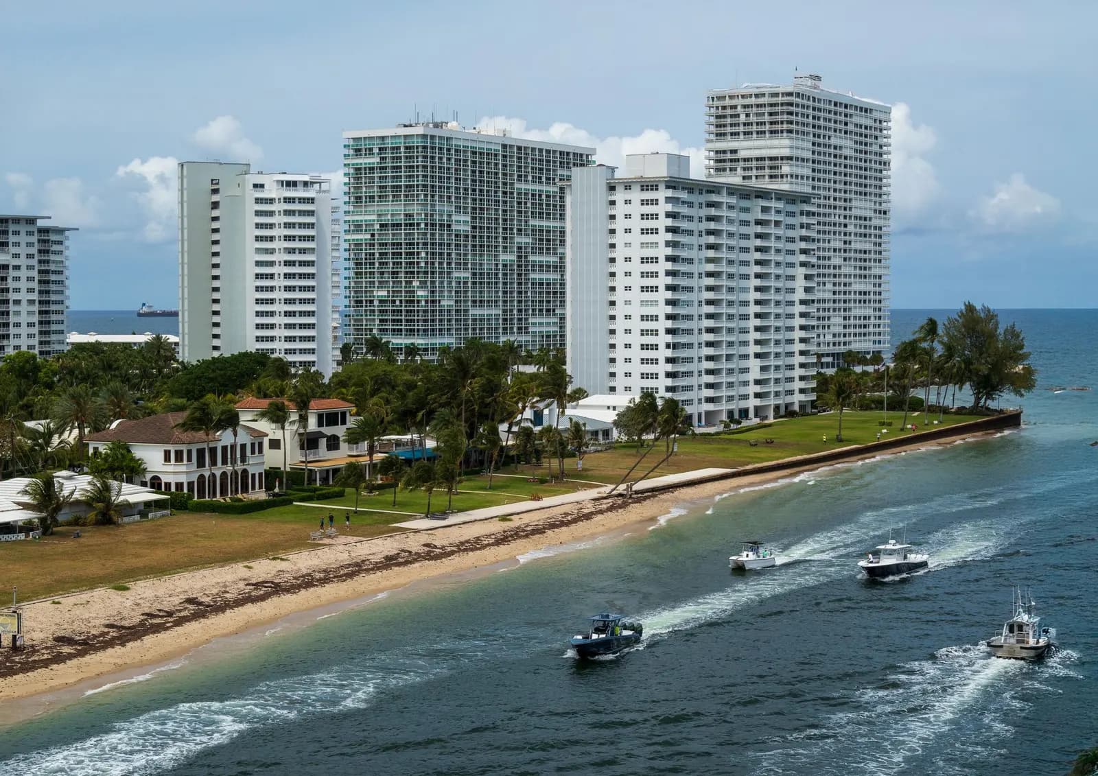 Inlet with condo towers, a beach and boats heading out to sea