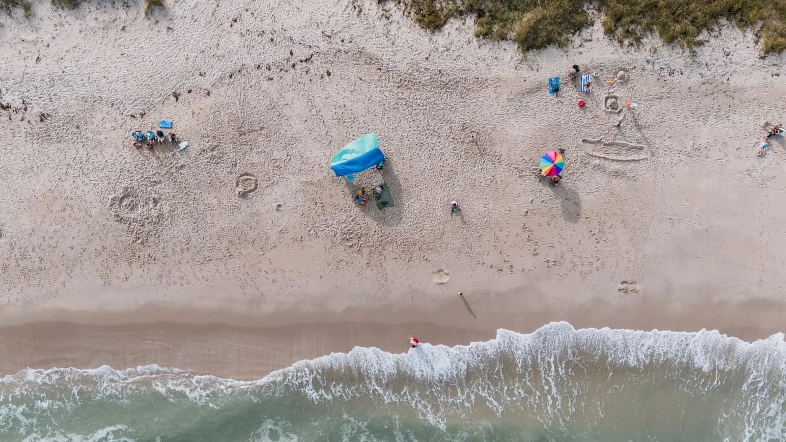 Aerial view of a sandy beach with umbrellas and the surf