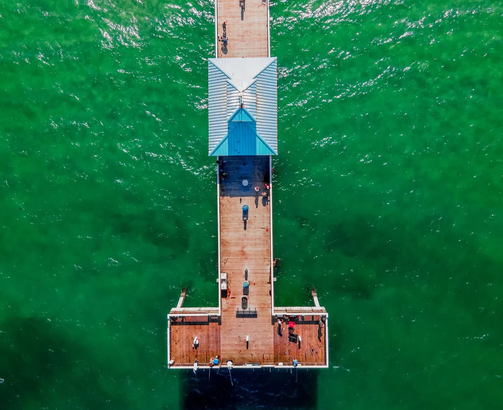 Aerial view of a fishing pier over green water