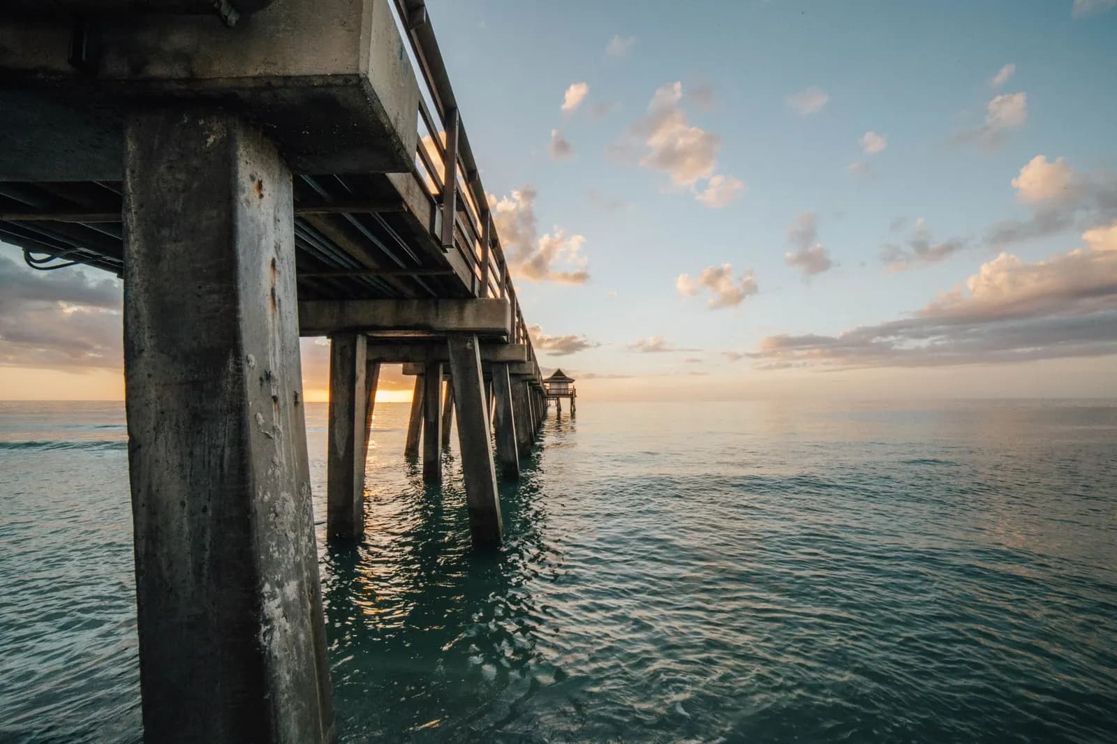 Looking along the underside of a wooden fishing pier at dawn