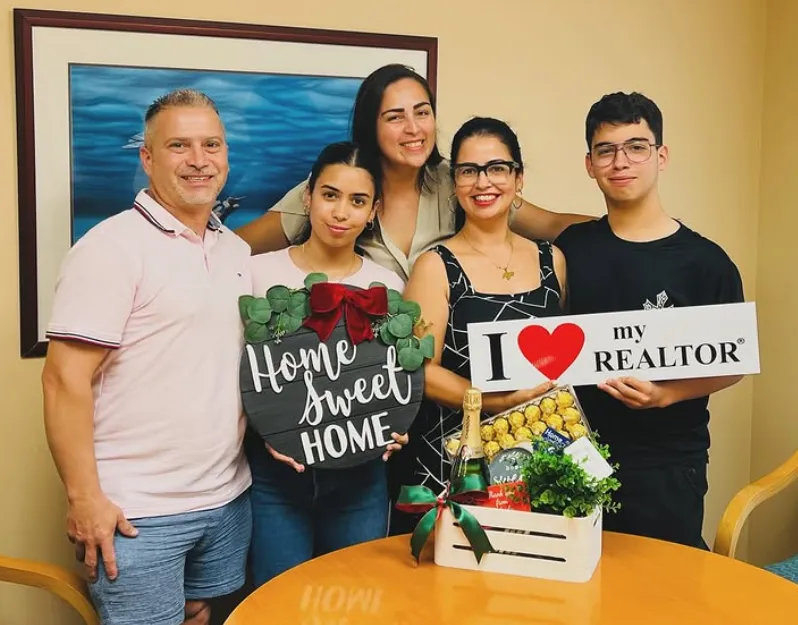 Closing day: clients with the Home Sweet Home sign, a thank-you sign and the gift basket