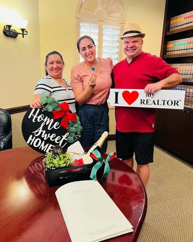 Closing day at the office: clients with the Home Sweet Home sign and the gift basket