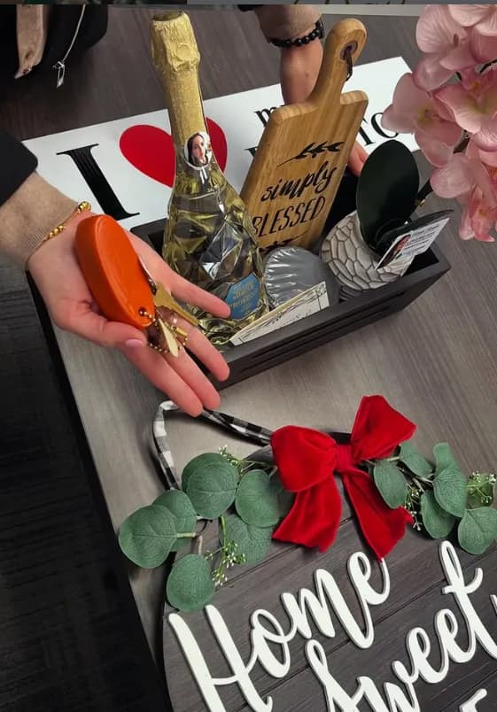 Keys in hand next to the closing-day gift box: champagne, a "simply blessed" board and the Home Sweet Home sign