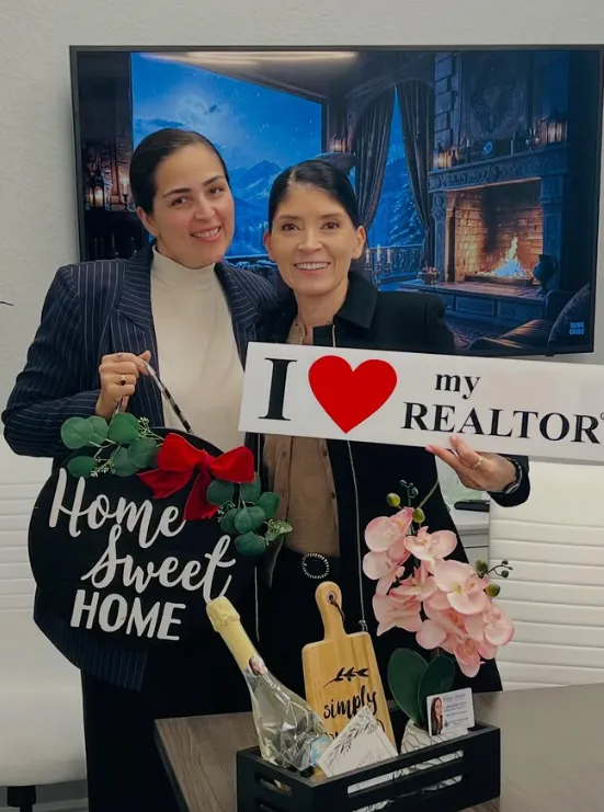 Gabriela with a client holding a thank-you sign and the Home Sweet Home wreath