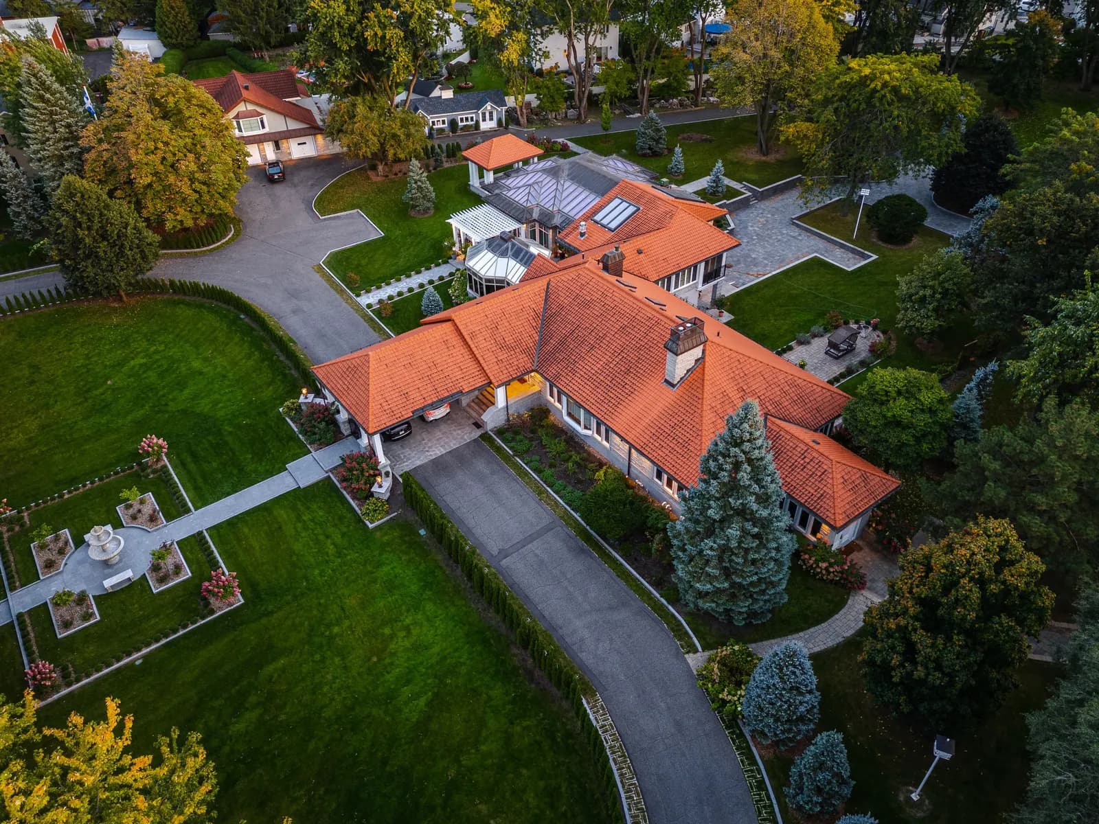 Aerial view of a home with a red tile roof surrounded by lawns and trees